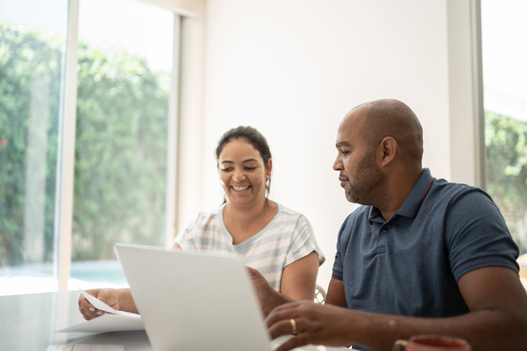 Smiling couple reviewing documents on a laptop, representing workers’ compensation claim filing deadlines in Louisiana.