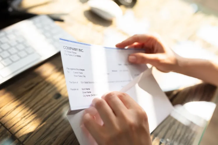 Person opening an envelope with a settlement check, representing workers' compensation claim settlements in Louisiana.