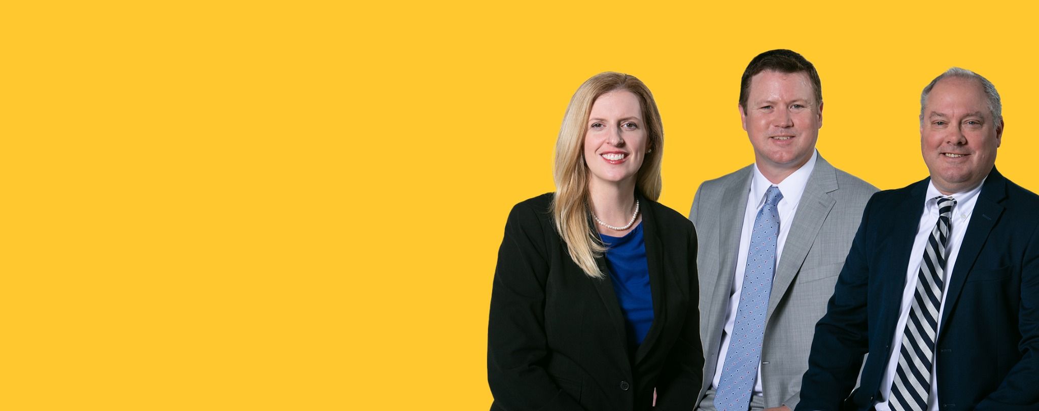 Three professional team members posing for a group photo against a yellow background, representing the Meet the Team page.