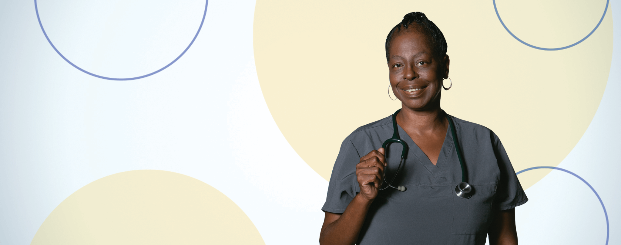 Smiling healthcare worker in gray scrubs holding a stethoscope, featured on the Workers’ Compensation FAQ page.